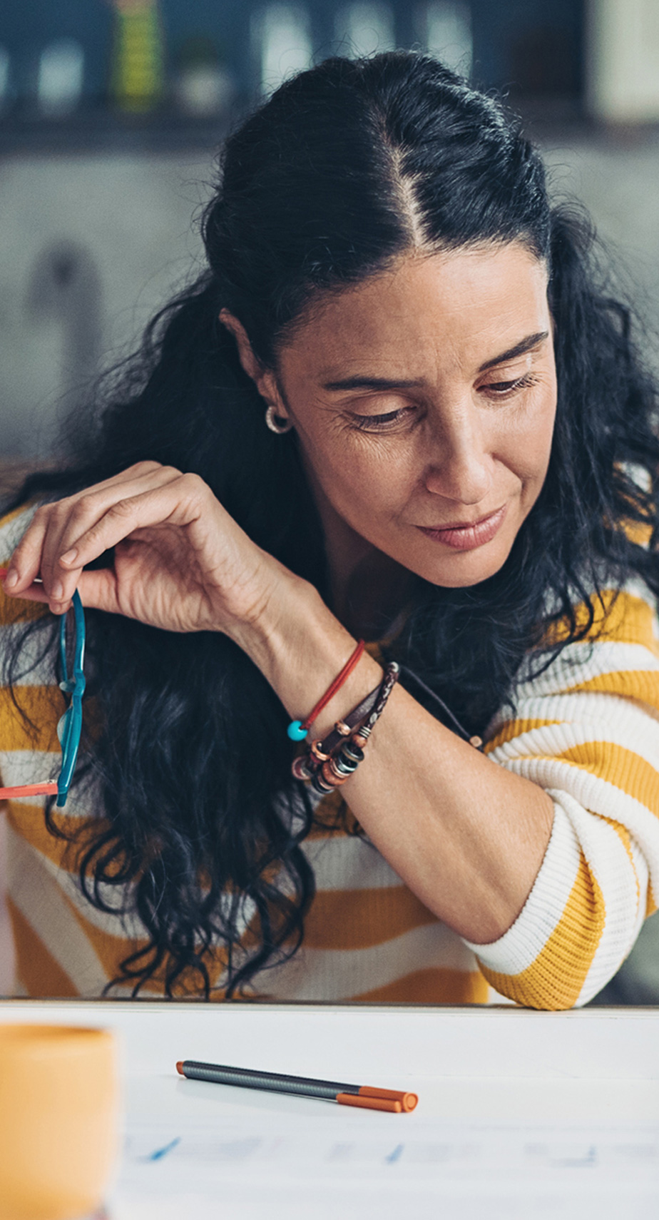 dark haired woman looking down with bracelets