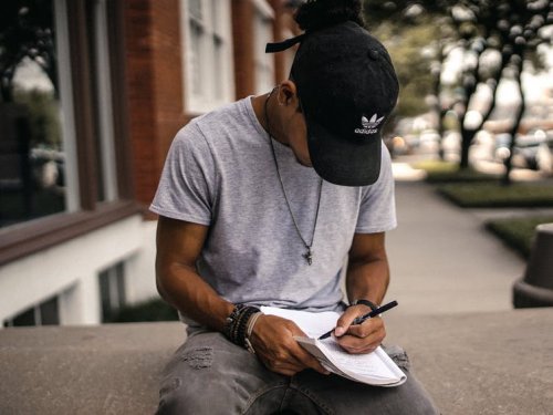 Boy with a cap writting on a notebook