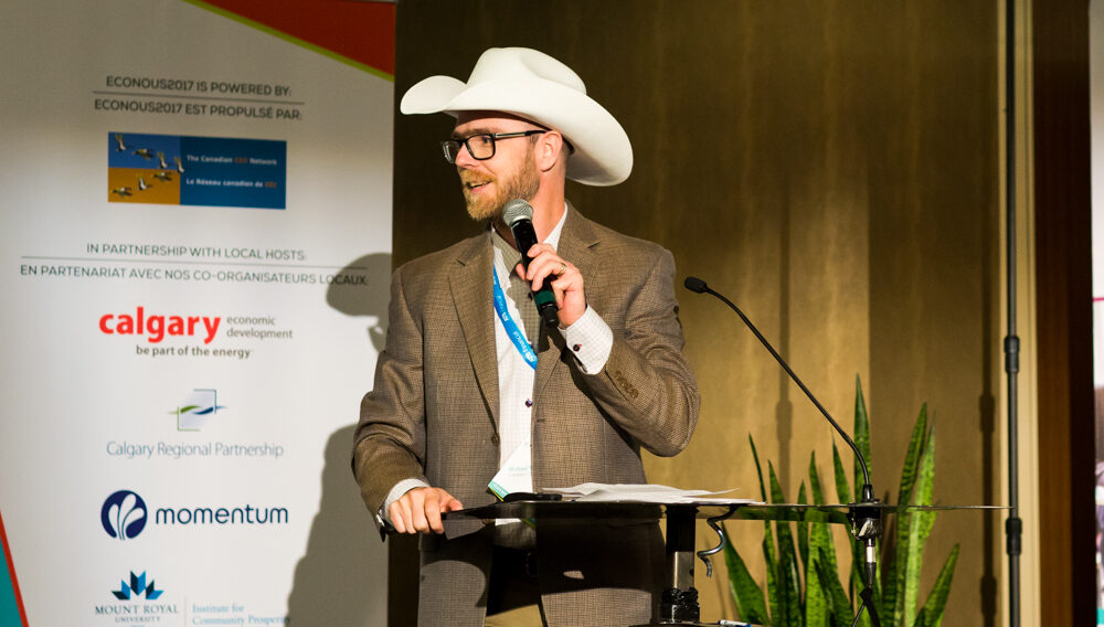 Mike Toye presenting at EconoUs2017 while wearing a white cowboy hat